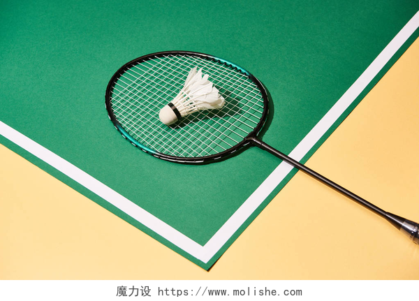 羽毛球馆的羽毛球和球拍带线的绿色和黄色表面上的金属羽毛球球拍和羽毛球